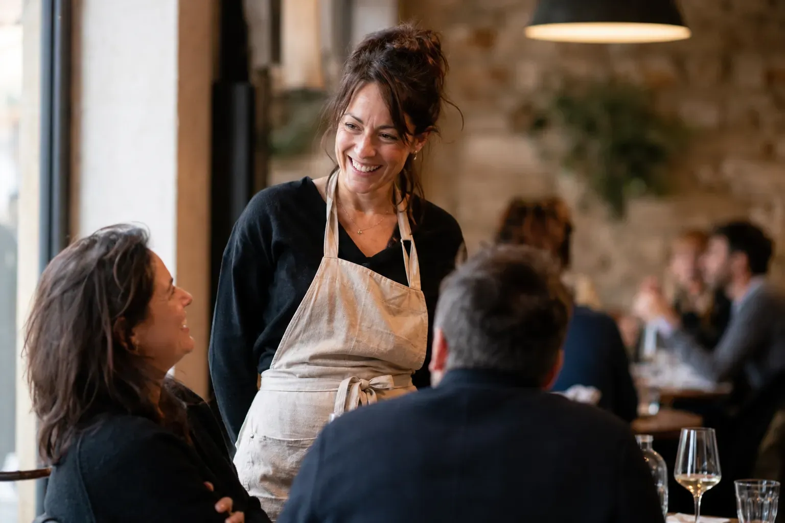 Uma empregada de mesa conversa com os clientes num restaurante